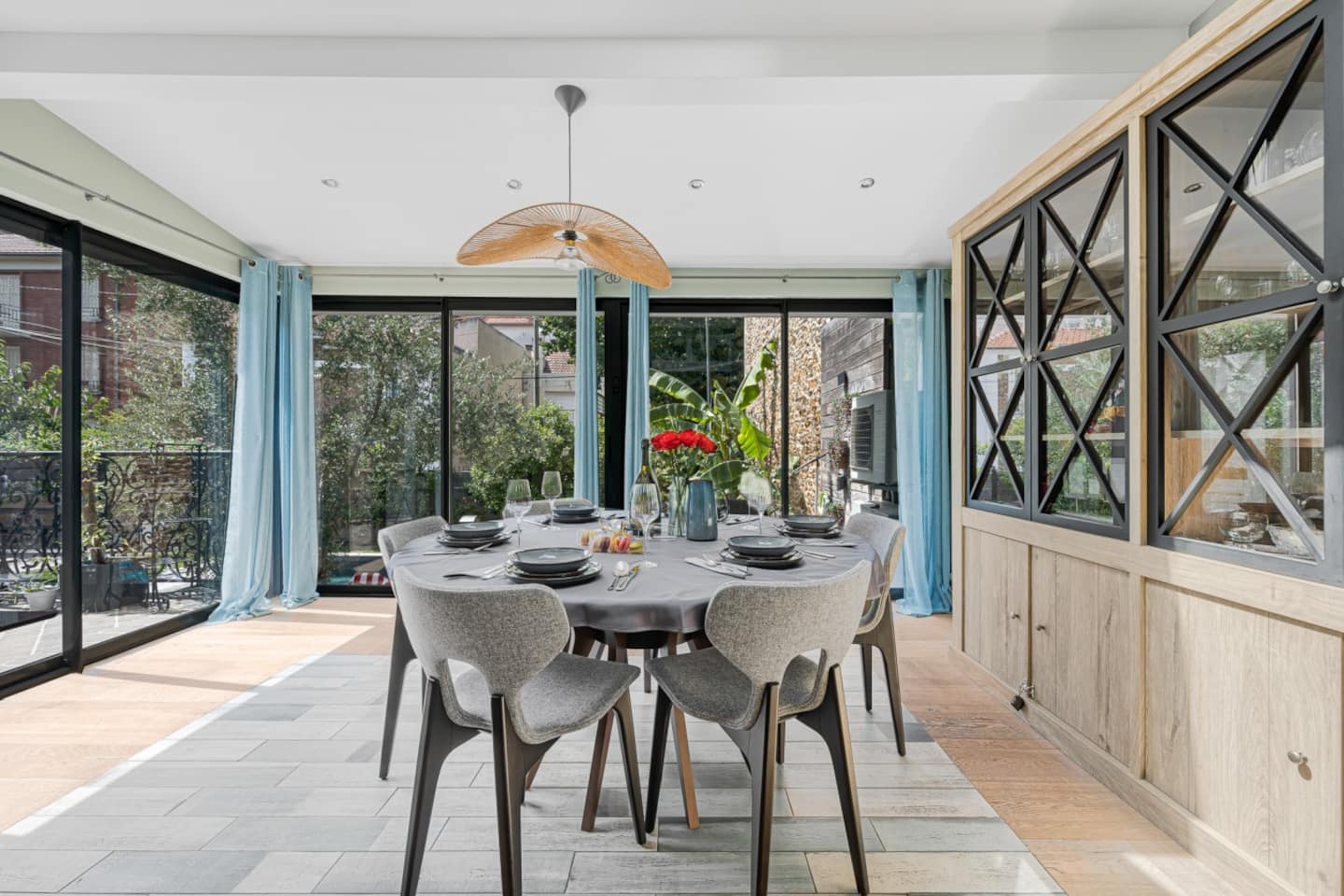 Salle à manger avec table ronde, chaises design et baies vitrées paysagères.