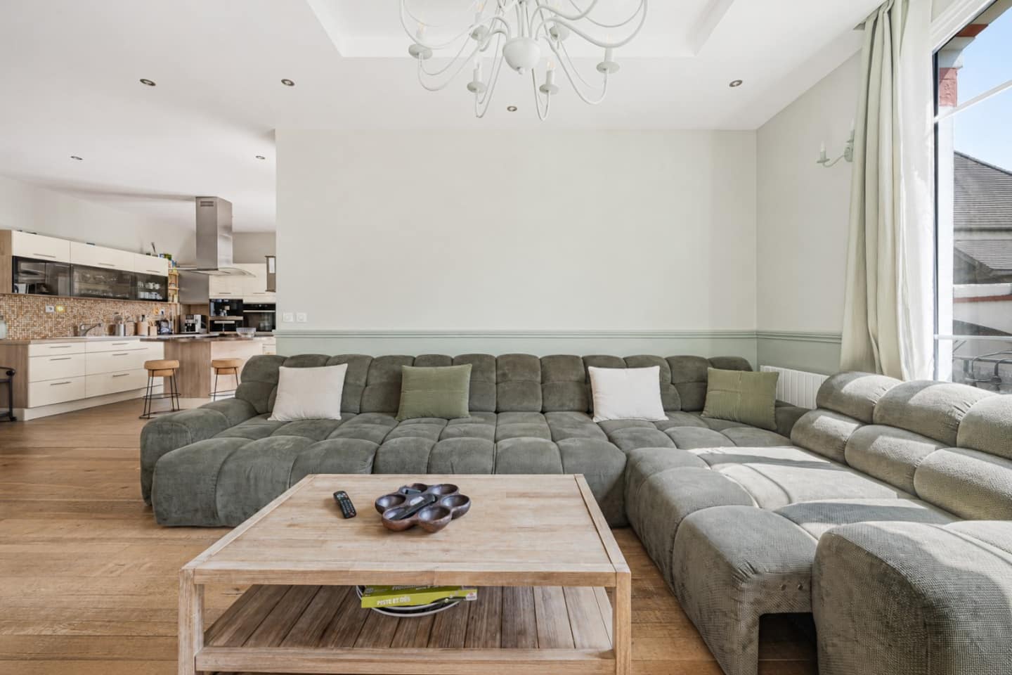 Séjour contemporain avec canapé modulable et grande luminosité naturelle.
