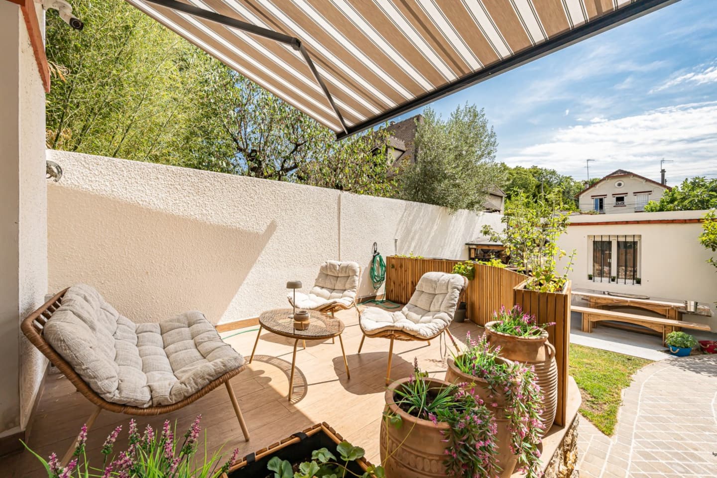 Terrasse aménagée sous auvent avec mobilier de détente et plantations.