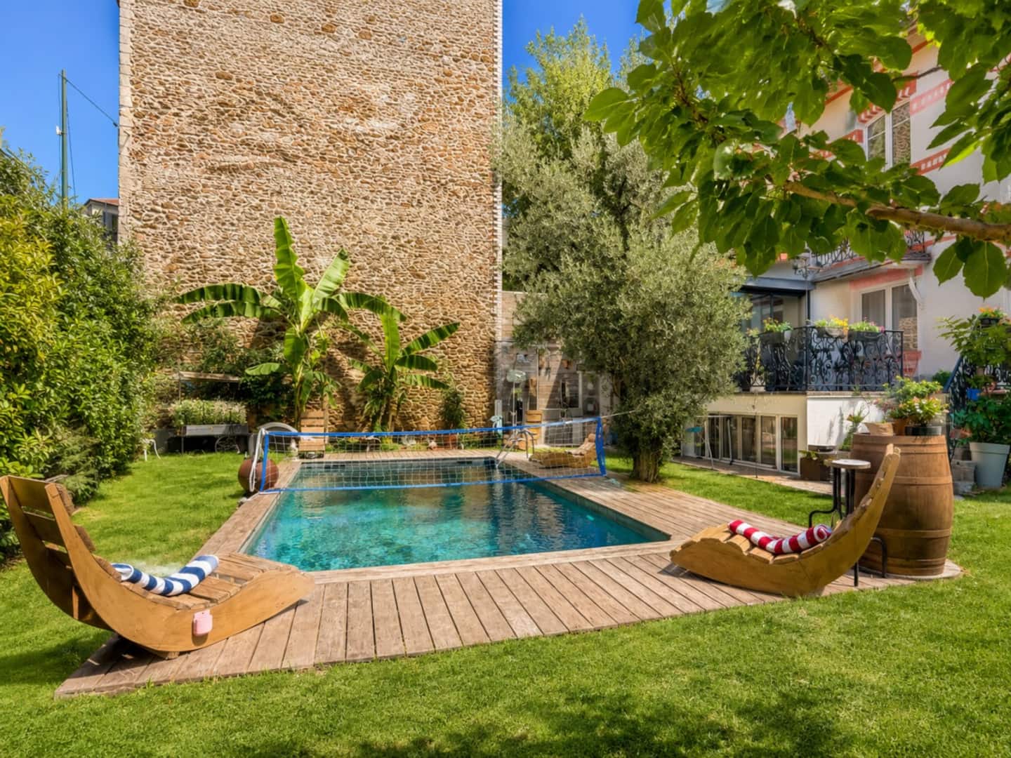 Piscine privée dans un jardin verdoyant avec chaises longues originales.