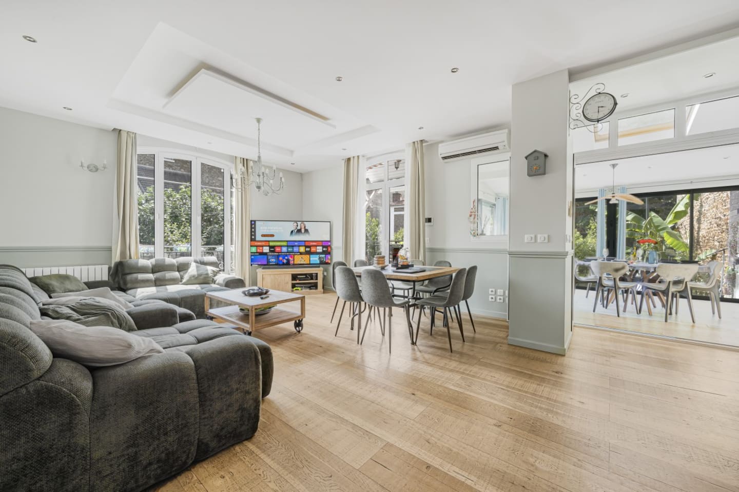 Salon traversant avec mobilier design et portes donnant sur le jardin.